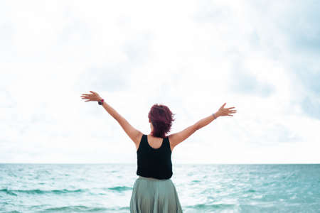 Woman rise hands up to sky freedom concept with sunset sky and summer beach season background.の写真素材
