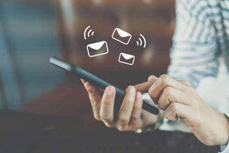 Woman hand using smartphone and it's show email recieve notification icon pop up on screen of mobile phone. Business communication  technology concept.の写真素材