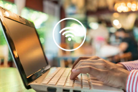 Woman hand using laptop with wifi icon in public place outdoor background. Business communication social network concept.の写真素材