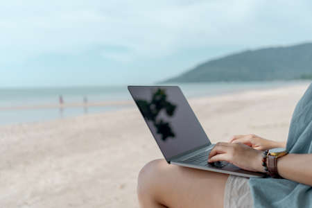 Woman using laptop and smartphone to work study in vacation cady at beach background. Business, financial, trade stock maket and social network concept.の写真素材