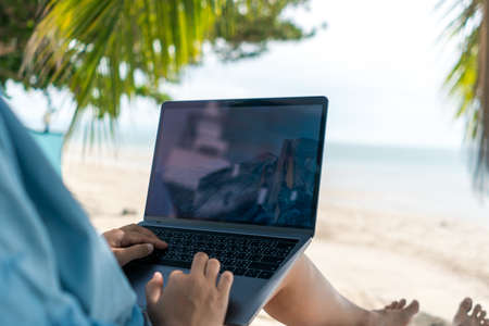 Woman using laptop and smartphone to work study in vacation cady at beach background. Business, financial, trade stock maket and social network concept.の写真素材
