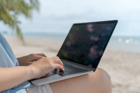 Woman using laptop and smartphone to work study in vacation cady at beach background. Business, financial, trade stock maket and social network concept.の写真素材