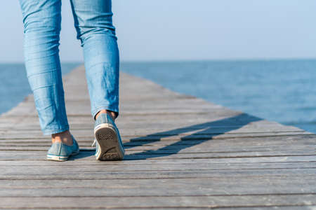 Woman is walking on small wood bridge to nature walk way with sunlight flare background.の写真素材