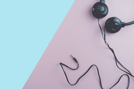 Top view of black headphones on white or pastel color background. Music concept.