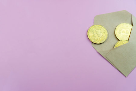 Top view of envelope with golden bitcoin coins as a gift. There are big golden BTC cryptocurrency...