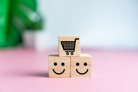 Smile face and cart icon on wood cube. Optimistic person or people feeling inside and service rating when shopping, satisfaction concept in business.の写真素材