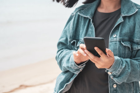 Woman using smartphone to do work business, social network, communication with beach outdoor...