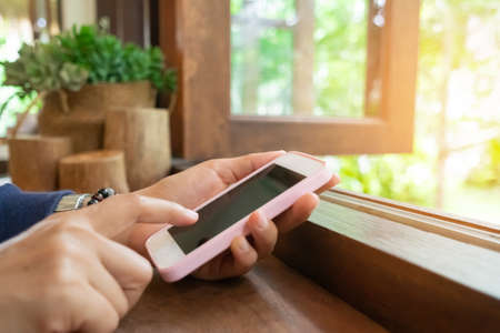 Woman hand using smartphone to do work business, social network, communication in public cafe work space.の写真素材