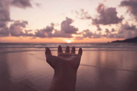 Woman hand reach out to sunset beach background.の写真素材