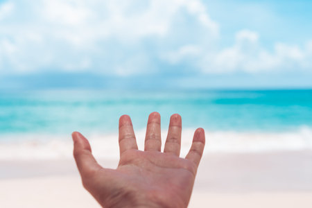 Woman hands reach out to the beach or blue sea background.