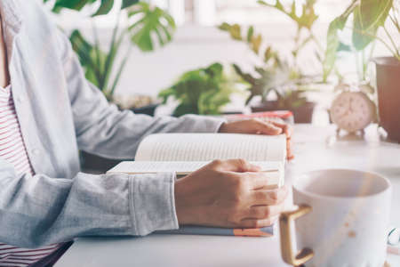 Woman is reading book in workspace area with nature background feeling relax and peaceful environment. Education business concept.の写真素材