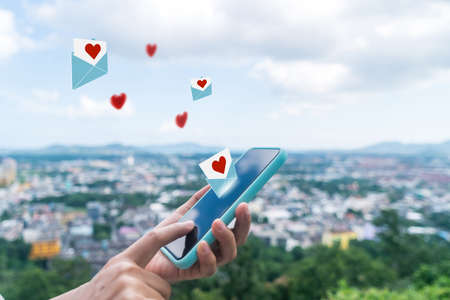 Hand typing love letter email in smartphone social network online community  with social media love letter mail send out icons valentine concept.の写真素材