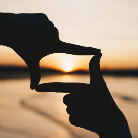Woman hands place together like praying from nature in front of sunset beach background.の写真素材