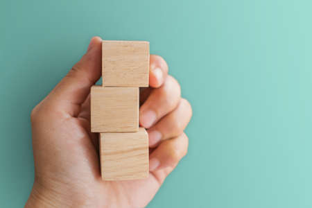 Blank wooden cube that you can put text or icon on in hand hold backgroundの写真素材