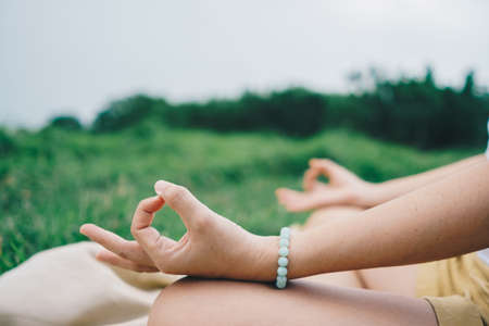 Woman practicing yoga lesson, breathing, meditating exercise, outdoor in grass field. Well being, wellness conceptの写真素材