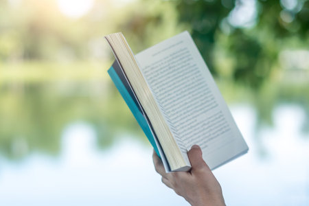 Woman is reading book in beautiful park and pond relax and peaceful environment background.の写真素材