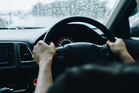 Hand of person on steering wheel drive a car with sunlight background.の写真素材