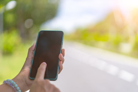 Woman hand use phone on the road and car background.の写真素材