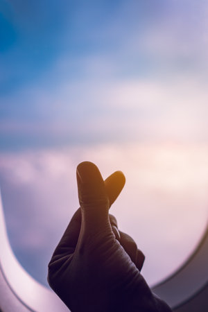 Hand do mini heart meaning love on airplane window.の写真素材