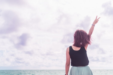 Young woman rise hand up to sky on summer beach background feel relax and energize.の写真素材