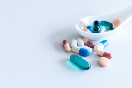 Medicine or vitamin pill spilt out of bottle or spoon on white floor background.の写真素材