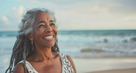 Portrait of a beautiful senior woman standing on the beach.の素材