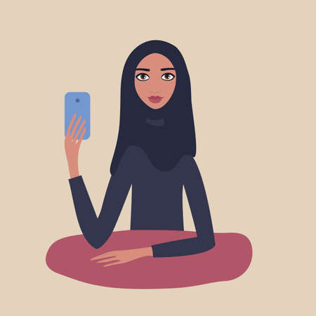 Lovely happy young girl Beautiful Muslim woman wearing hijab sitting at table holding mobile phone in her hand Taking picture Make selfie Modern Technology concept Beige background Pretty Cute Lovely.のイラスト素材