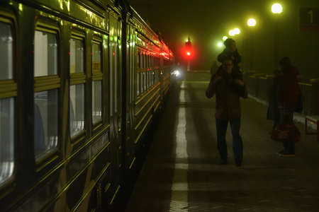 Dubna, Russia - 5 November, 2018: Commuter train and passengers in Dubna railway station in dense fog at night.のeditorial素材