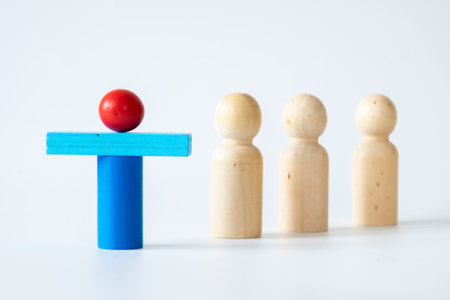 Creative arrangement of a red and blue wooden block figure standing in front of three plain wooden peg figures on a white background, concept of leadership or individuality.の写真素材