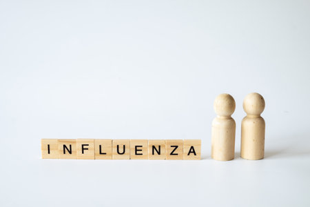 Wooden letter blocks spelling 'INFLUENZA' aligned on a white background with two peg figures, representing health, flu, and medical concepts in education.の写真素材