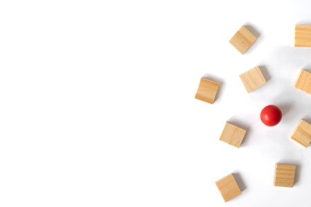 A single red ball surrounded by scattered wooden blocks on a white background, illustrating individuality, contrast, and leadership in creative thinking.の写真素材