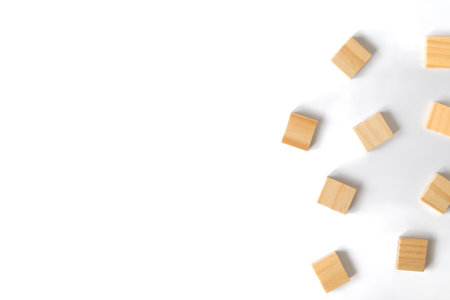 Several small wooden blocks are scattered on the right side of a clean white background, illustrating randomness, simplicity, and creative potential in minimal design.の写真素材