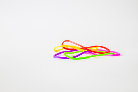 A set of vibrant colorful rubber bands arranged on a minimalist white surface, symbolizing variety and flexibility in creative concepts.の写真素材
