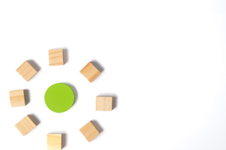 A single green circle is surrounded by scattered wooden blocks on a white background, illustrating focus, growth, and unity in creative conceptual design.の写真素材