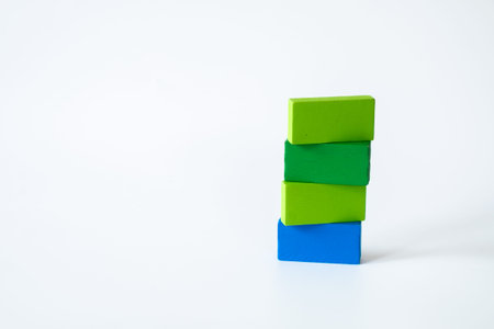 Three green and one blue rectangular wooden blocks stacked in a creative arrangement on a white...