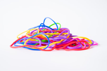 A bright pile of colorful rubber bands arranged in a playful heap on a clean white background, symbolizing creativity and unity in diversity.の写真素材