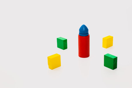 Colorful geometric wooden blocks, including cubes and a cylinder with a blue tip, arranged on a clean white background.の写真素材