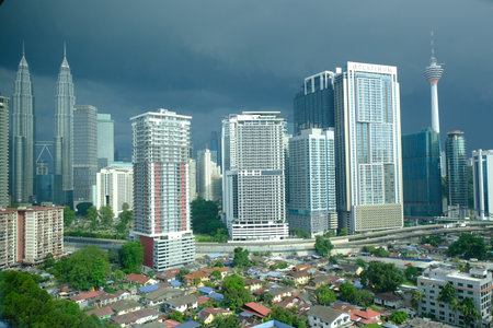 Kuala Lumpur, Malaysia - November 2, 2025: Petronas Twin Towers, KL Tower and city buildings seen under dramatic dark clouds above urban neighbourhoods.のeditorial素材