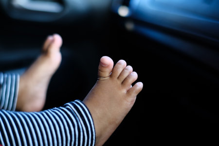 Close-up of two small baby feet with tiny toes wearing striped sleepwear. Focus on innocence, growth, and new life.の写真素材