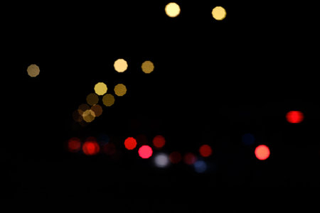 Abstract background of car head and tail lights bokeh at night, featuring red and golden...