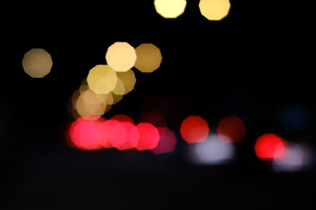 Abstract background of car head and tail lights bokeh at night, creating red and golden hexagonal shapes.の写真素材