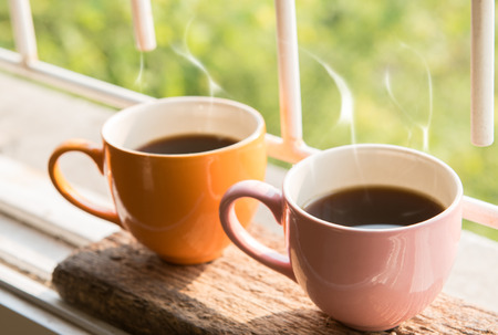 Coffee cup at window on the morning with beautiful nature and lighting backgroundの写真素材