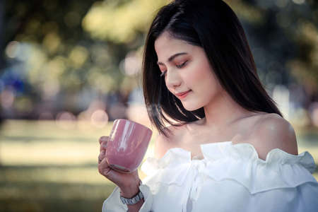 One women in Public park drink coffee and read a book relaxed at bangkok city thailandの写真素材