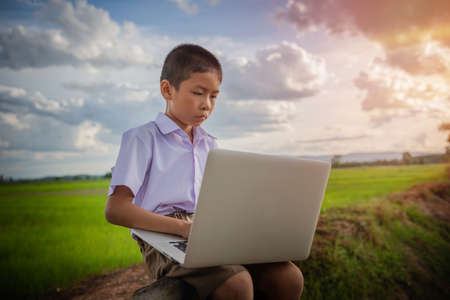 Thai boy and computer in Rice field Chiang Rai Province Thailand Asiaの写真素材