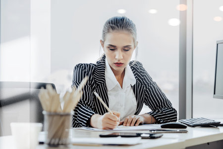 People working on laptop at their desk with manager supervising the work. Business people working in...