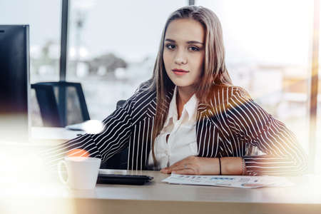People working on laptop at their desk with manager supervising the work. Business people working in a small office.の写真素材