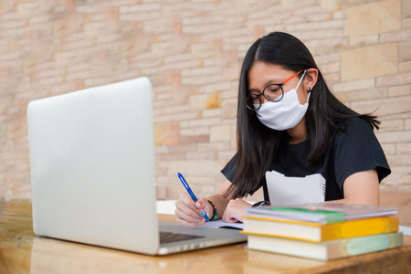 Junior high school girl Do homework at home Because the school is closed Due to the severe outbreak...