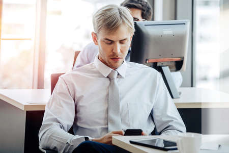 People working on laptop at their desk with manager supervising the work. Business people working in a small office.の写真素材
