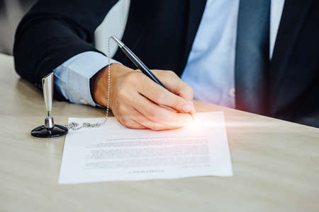 People working on laptop at their desk with manager supervising the work. Business people working in a small office.の写真素材