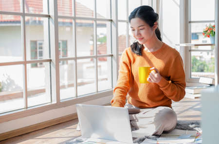beautiful teen students studying and working at home From the pandemic of the Coronavid virus, Covid-19, caused the new normal worldwide. for social distancing, she Is using a notebook computer in her houseの写真素材